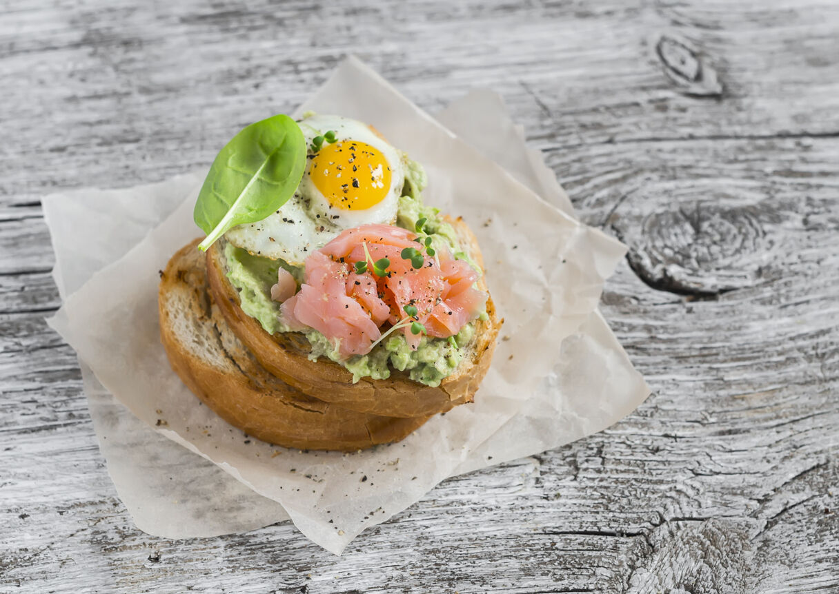 Mashed avocado sandwich with smoked salmon and fried quail egg.