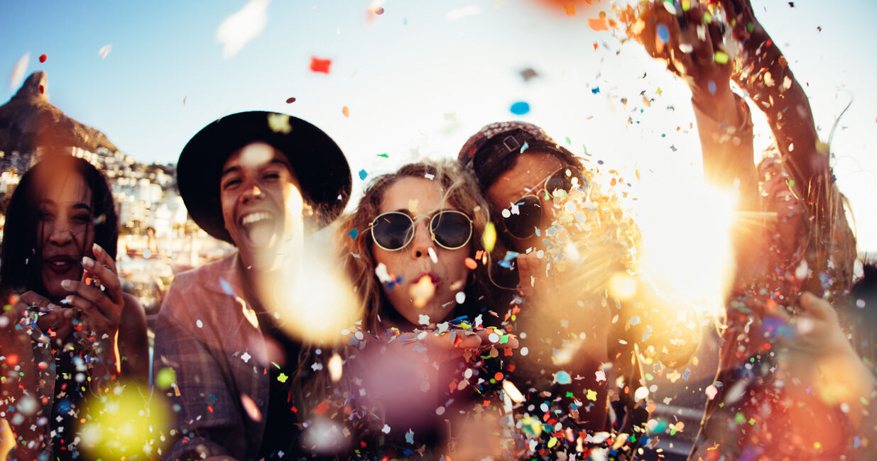 Teenager hipster friends partying by blowing colorful confetti from hands