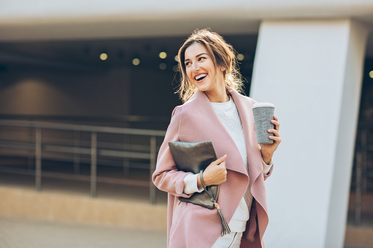 Elegant young woman walking on the sidewalk at urban setting and looking back.