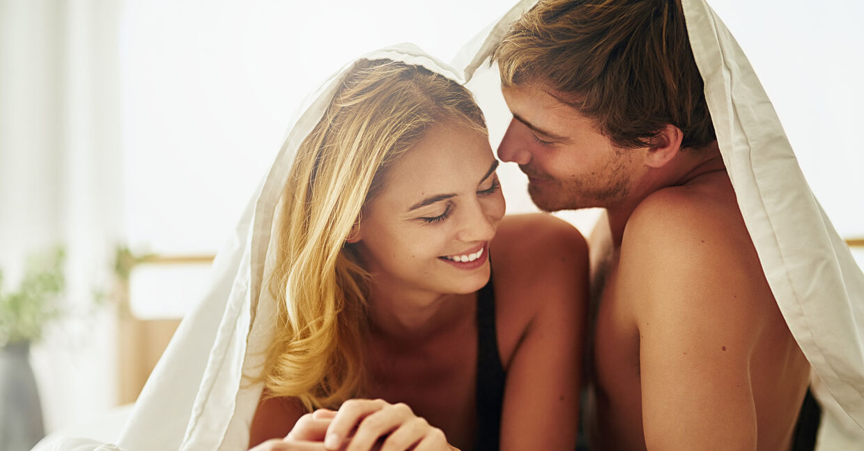 Shot of a young couple sharing an intimate moment under the covers in bed