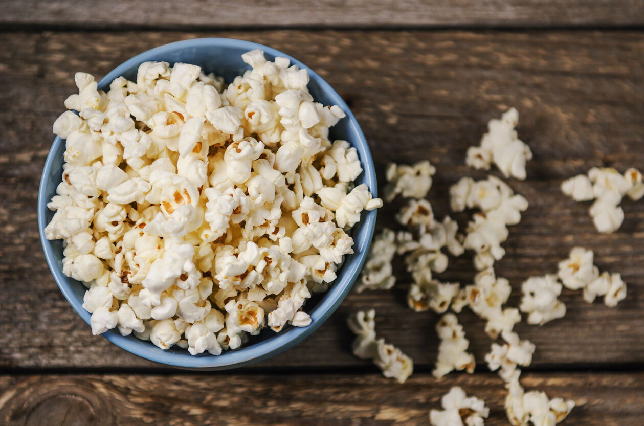 Popcorn in a blue bowl on wooden table