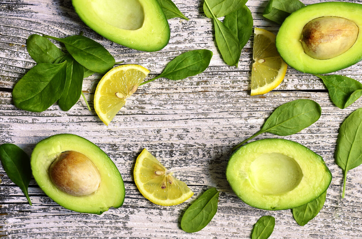 Cut avocado with baby spinach leaves and lemon slices.