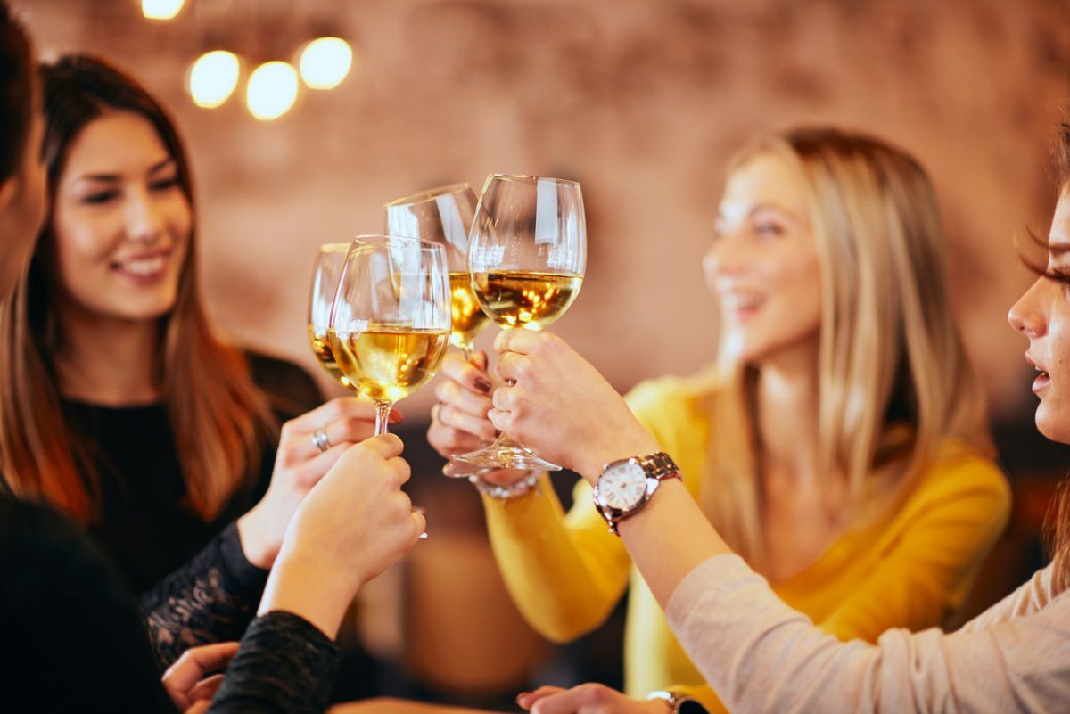 Girlfriends drinking wine and chatting while sitting in the bar.