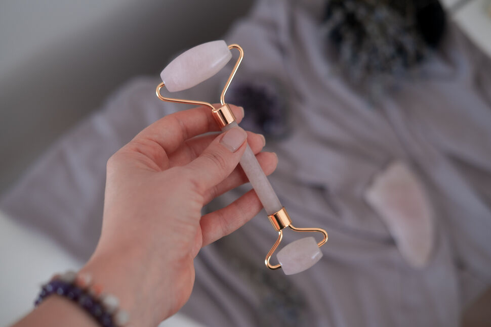 Rose quartz roller in woman's hand. Beauty anti-ageing concept. Top view