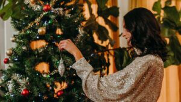 Een jonge vrouw versiert haar kerstboom.