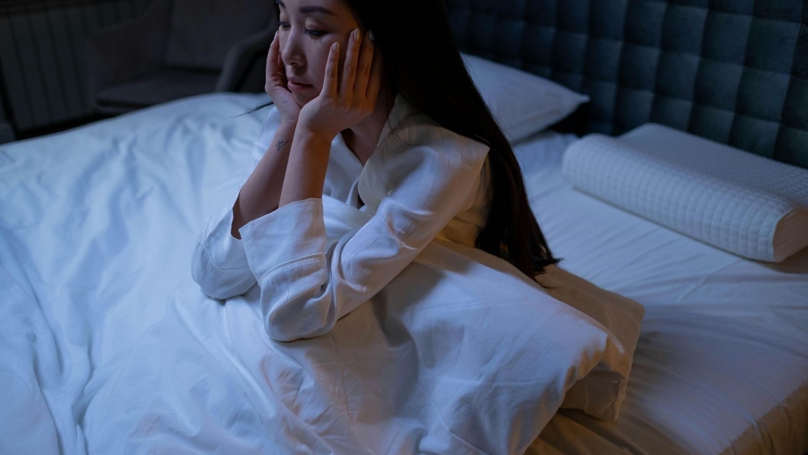 Een vrouw zit in bed.