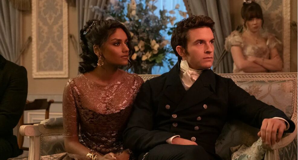 Anthony en Kate zitten naast elkaar op de bank in de serie Bridgerton.
