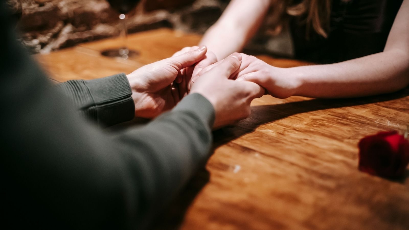 Man en vrouw houden handen vast op tafel.