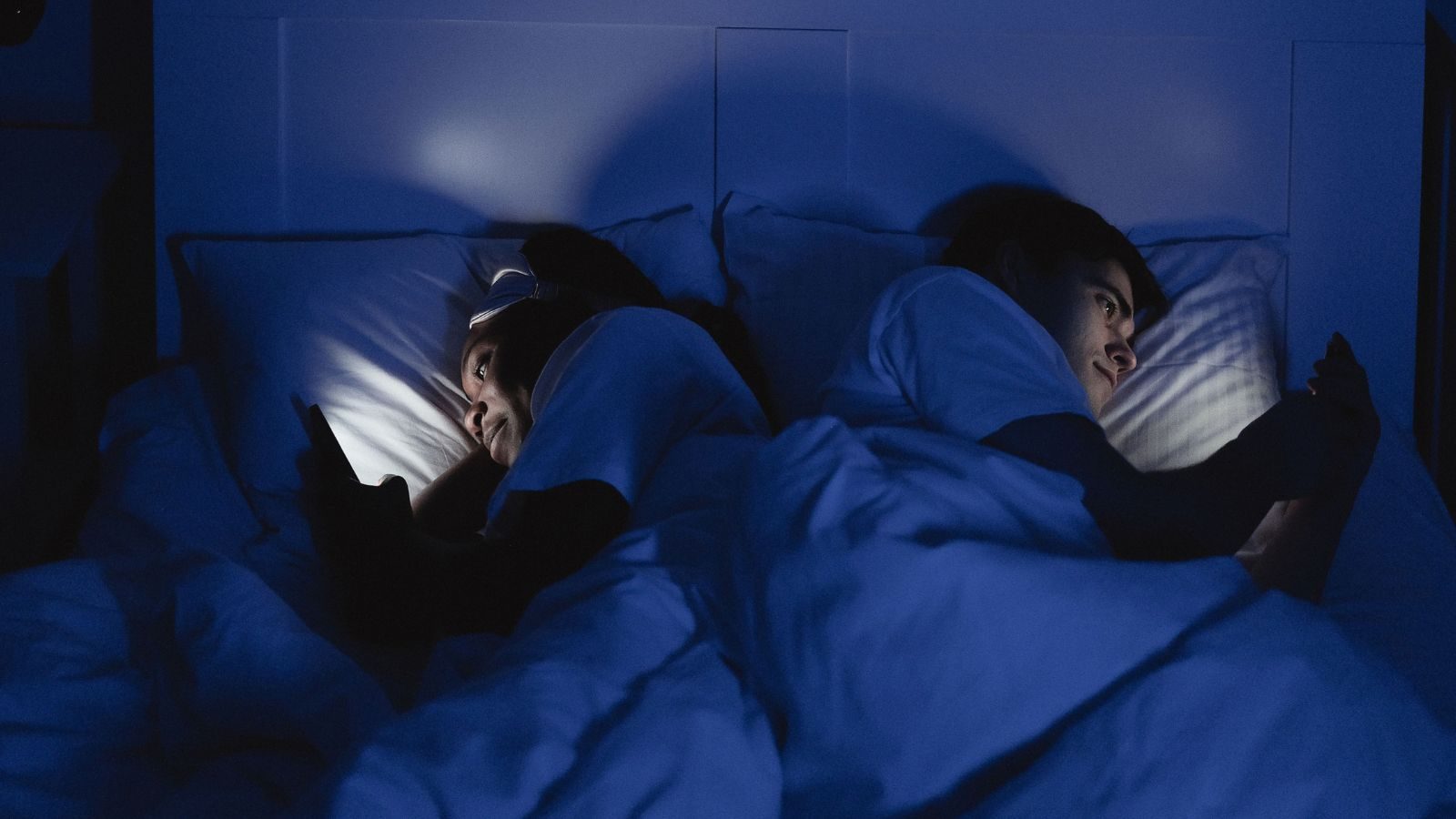 Man en vrouw in bed met telefoon.