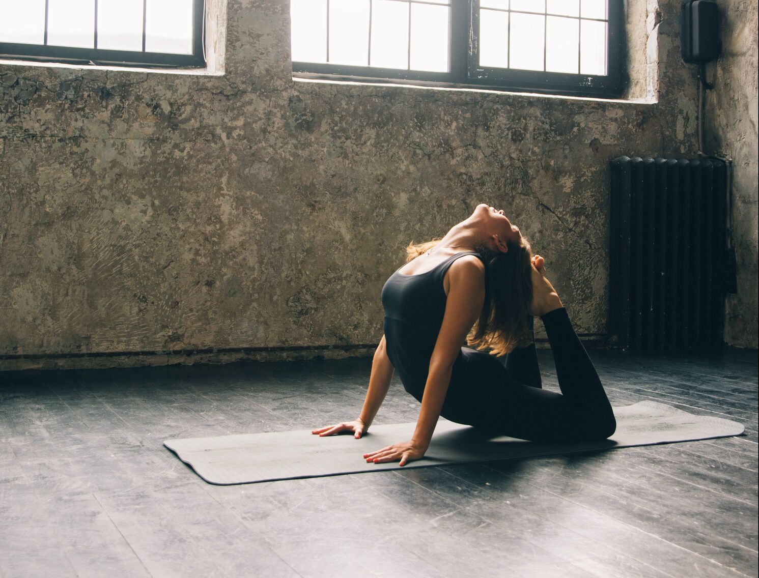 Young woman practicing yoga in urban loft: Cobra Pose (Bhujangasana)