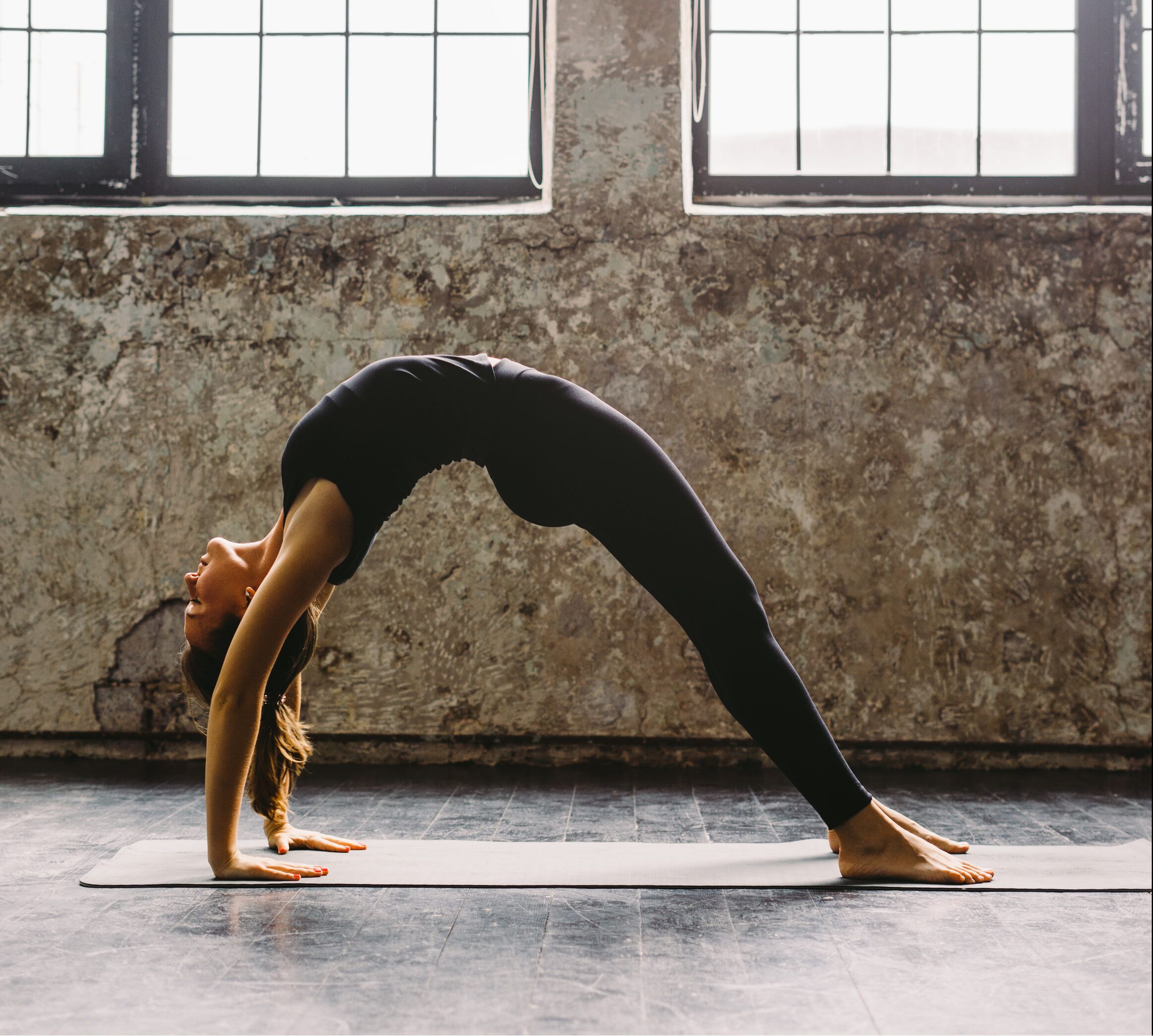 Young woman practicing yoga in urban loft: Upward Bow Pose