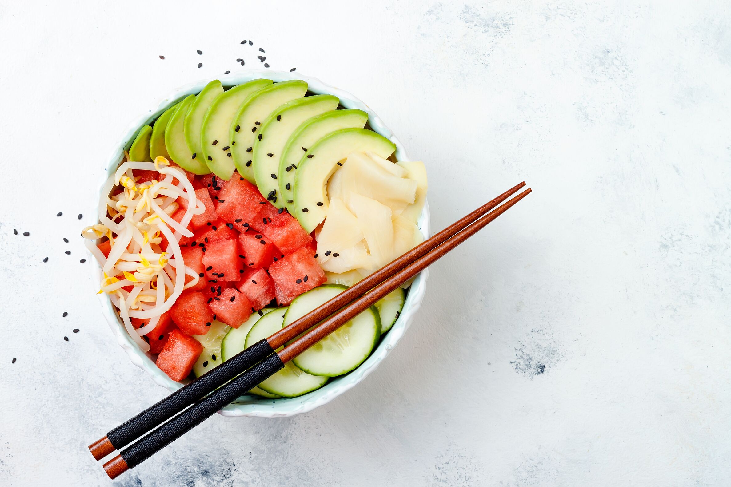 Hawaiian watermelon poke bowl with avocado, cucumber, mung bean sprouts and pickled ginger. Top view, overhead, flat lay, copy space