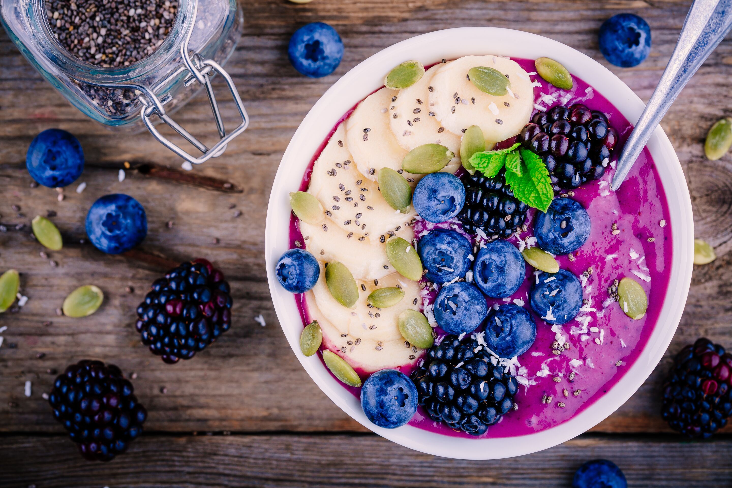 Smoothie bowl with fresh blackberries, blueberries, banana, sunflower seeds, pumpkin seeds, chia seeds and coconut