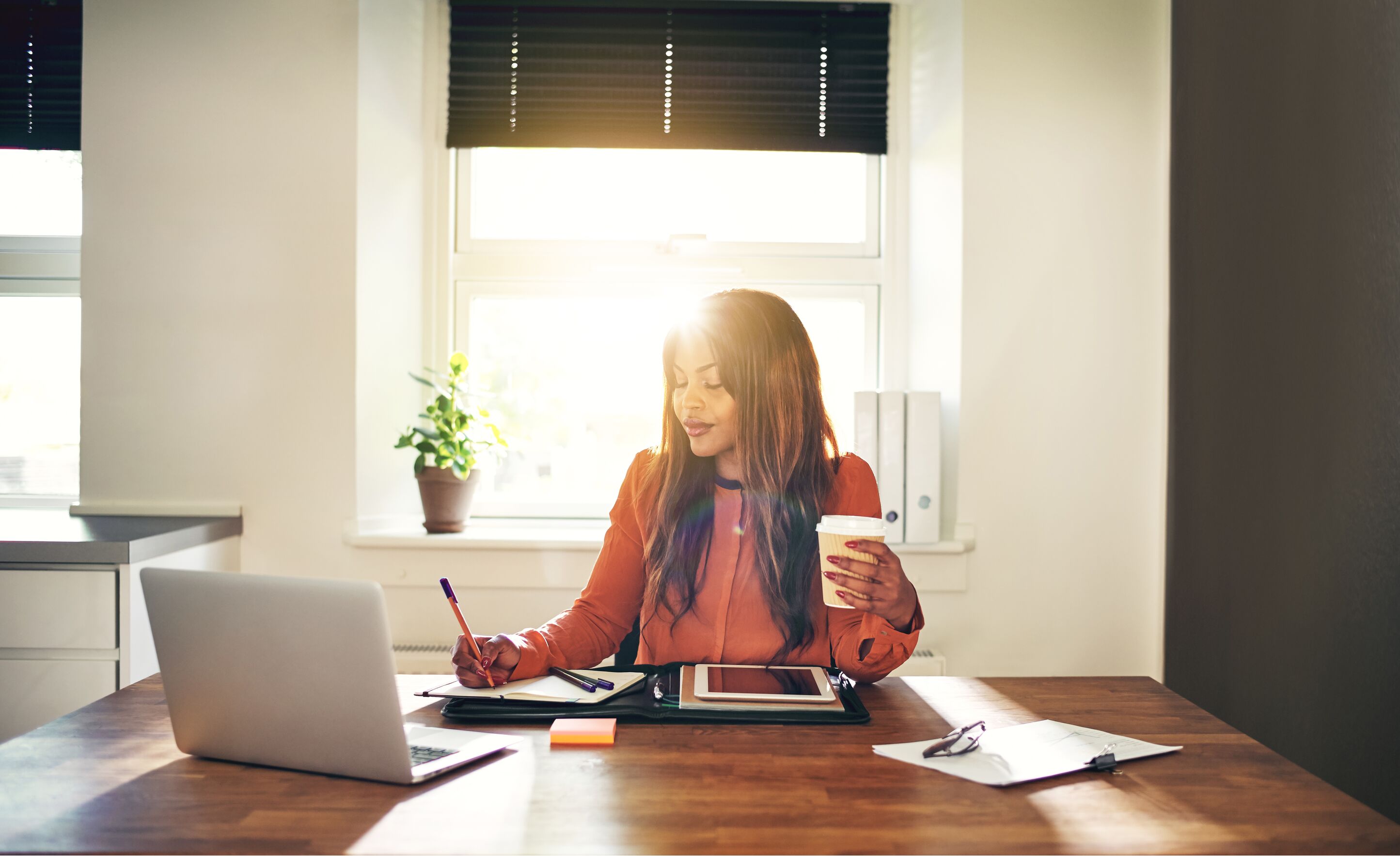 Smiling young female entrepreneur drinking coffee and working at home