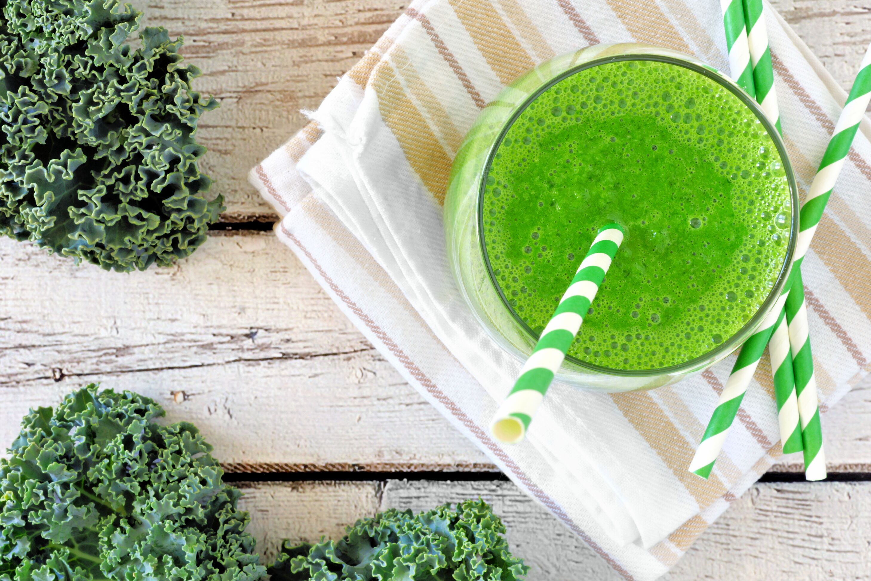 Green kale smoothie with straws overhead view