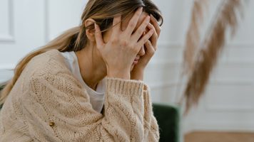 Vrouw met hoofd in handen.