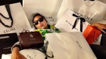 Een vrouw ligt in allemaal desigertassen.