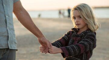 Jong meisje houdt de hand van haar vader vast.