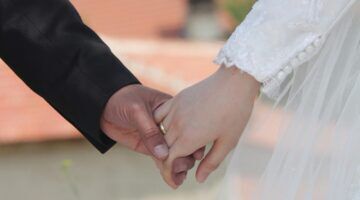 Bruid en bruidegom houden elkaars hand vast.