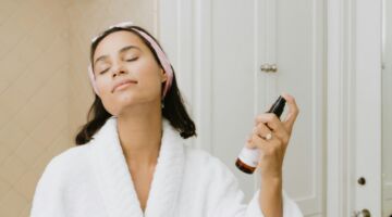 Vrouw spuit haar gezicht in met skincare product.