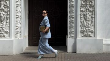 Vrouw loopt in pale blue outfit over straat.