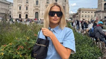 Rita Ora in blauw shirt met zwarte tas en zonnebril.