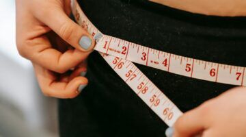 Vrouw meet haar heupen op