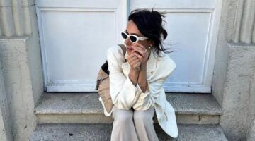 Vrouw met crèmekleurige outfit en witte zonnebril