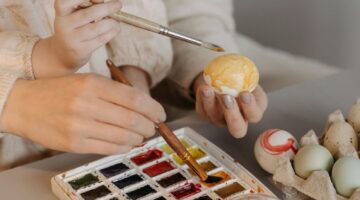 Moeder en kindje schilderen samen eieren.