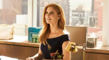 Donna Paulsen lachend aan haar bureau in de serie Suits.