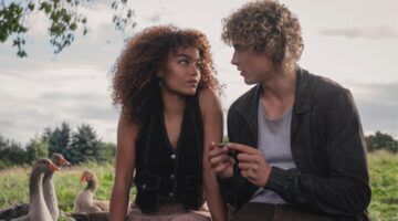 Personages uit de nieuwe Hunger Games film in de natuur kijkend naar elkaar.