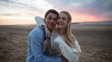 Personages van Knokke Off omhelzen elkaar op het strand.