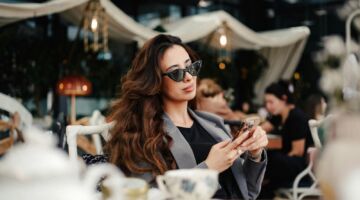 Vrouw zit op het terras op haar telefoon.