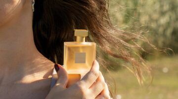 Vrouw houdt een flesje parfum vast.