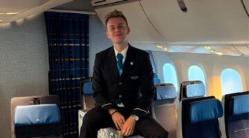 Steward en purser Michael de Vos zit in een vliegtuig en lacht naar de camera.