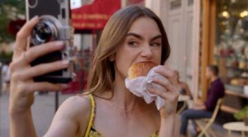 Emily eet een hamburger terwijl ze een selfie maakt.