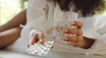 Vrouw met glas water en pillen om te slikken
