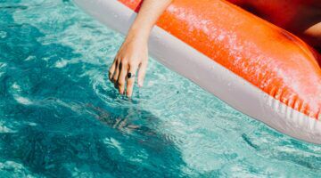 Luchtbed in het water met een hand er naast.