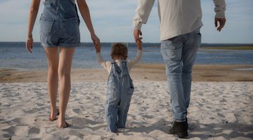 Kindje met ouders op het strand.