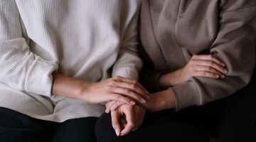 Vrouwen houden elkaars handen vast,