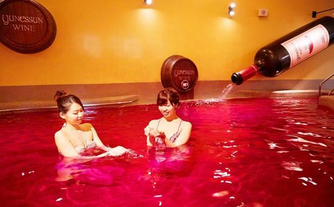 Illustratie voor: In deze spa in Japan kun je zwemmen in een bad gevuld met rode wijn