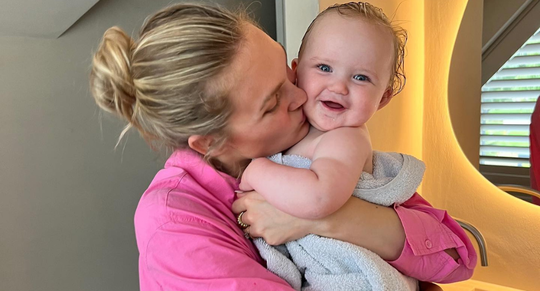 Een jonge moeder knuffelt haar baby.