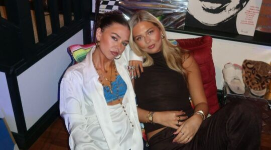 Twee vriendinnen lachen samen naar de camera.