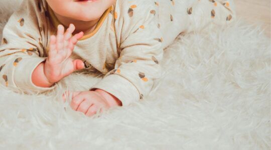 Baby ligt op een kleedje.