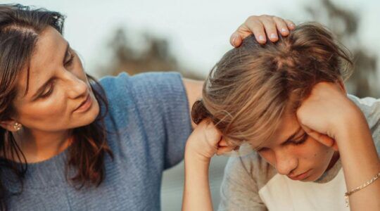 Een moeder aait haar zoon over het hoofd.