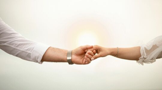 Twee mensen houden elkaars handen vast.