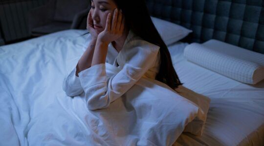 Een vrouw zit in bed.