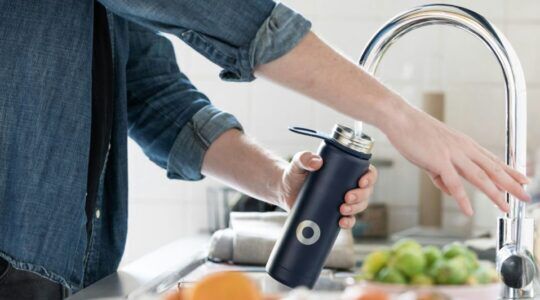 Iemand doet water in een waterfles.