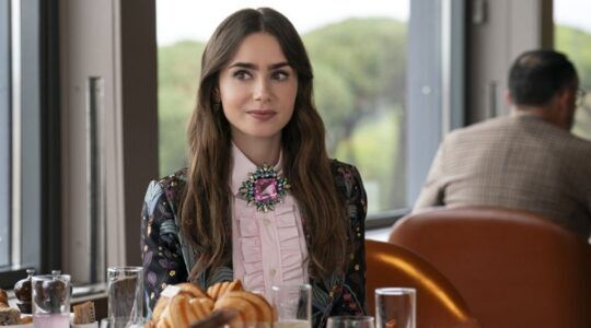 Emilt aan tafel in Emily in Paris.