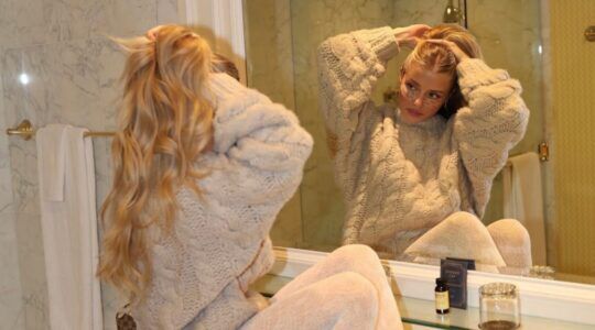 Vrouw die in de spiegel kijkt en haar haar vasthoudt